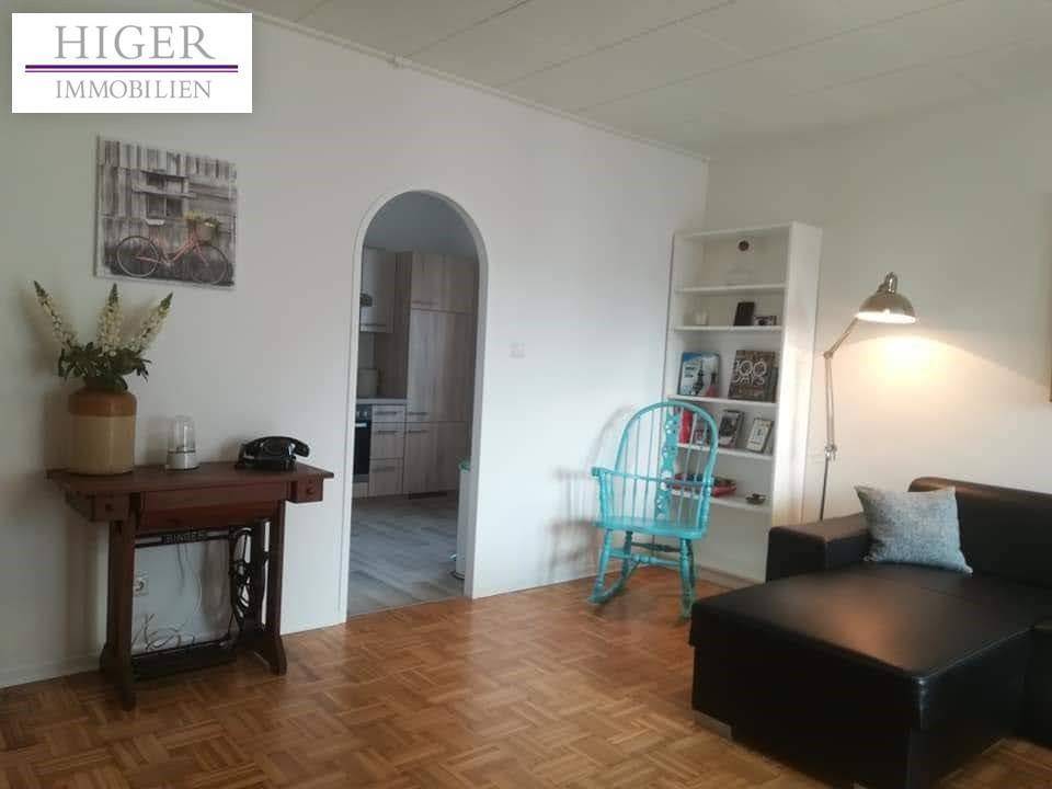 Gemütliches Wohnzimmer mit Parkettboden und offenem Durchgang zur Küche.