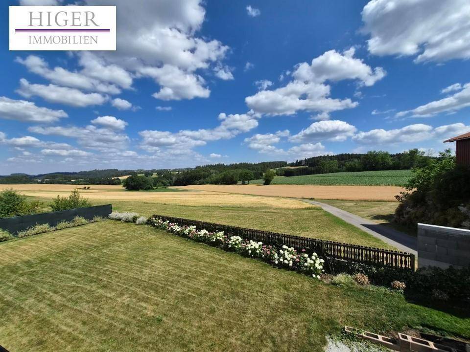 Weitläufiger Gartenbereich mit Blumenbeet und freiem Blick auf die umliegende Landschaft.