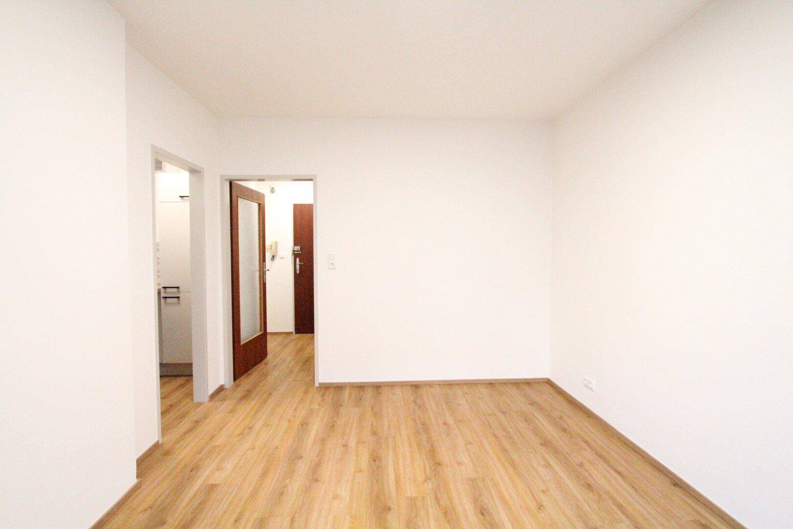 Heller Flur mit Laminatboden und Zugang zu verschiedenen Räumen der Wohnung.