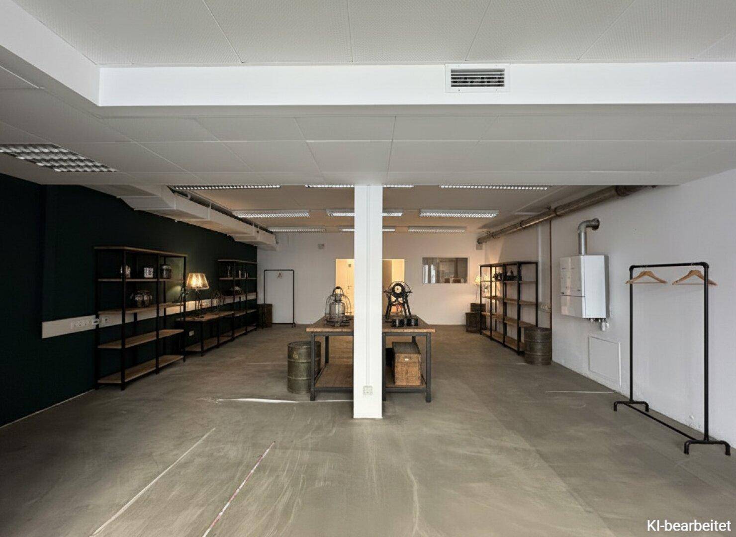 Heller Gewerberaum mit weißer Decke, Betonboden und einer dunkelgrünen Akzentwand, vielseitig nutzbar.