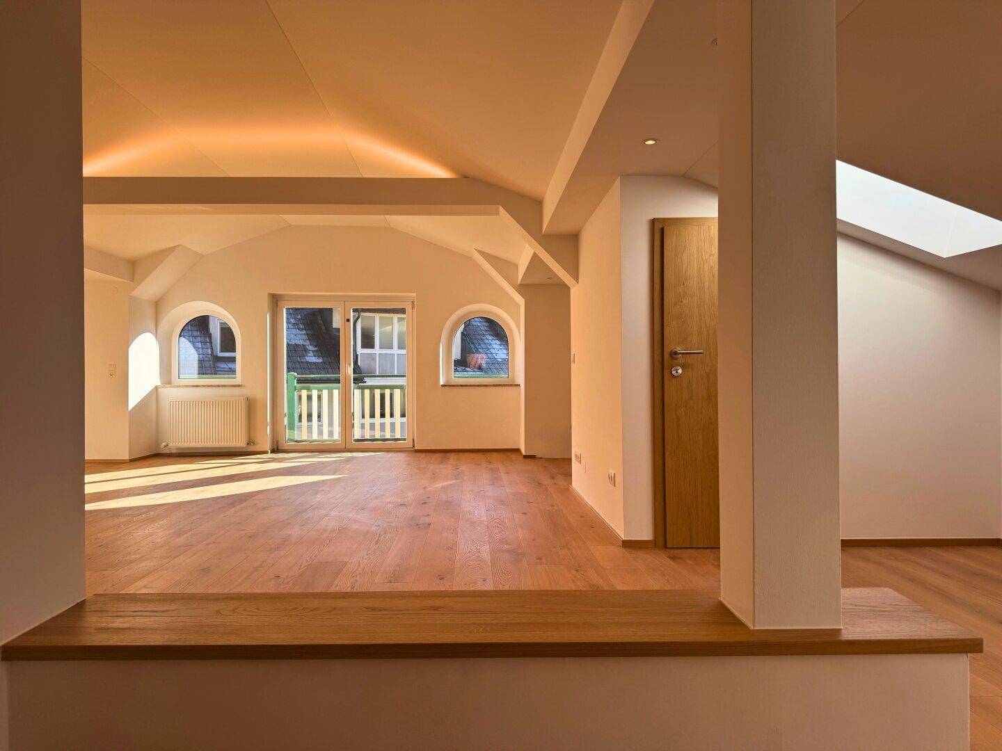 Heller Eingangsbereich mit Holzboden, der in den offenen Wohnbereich führt.