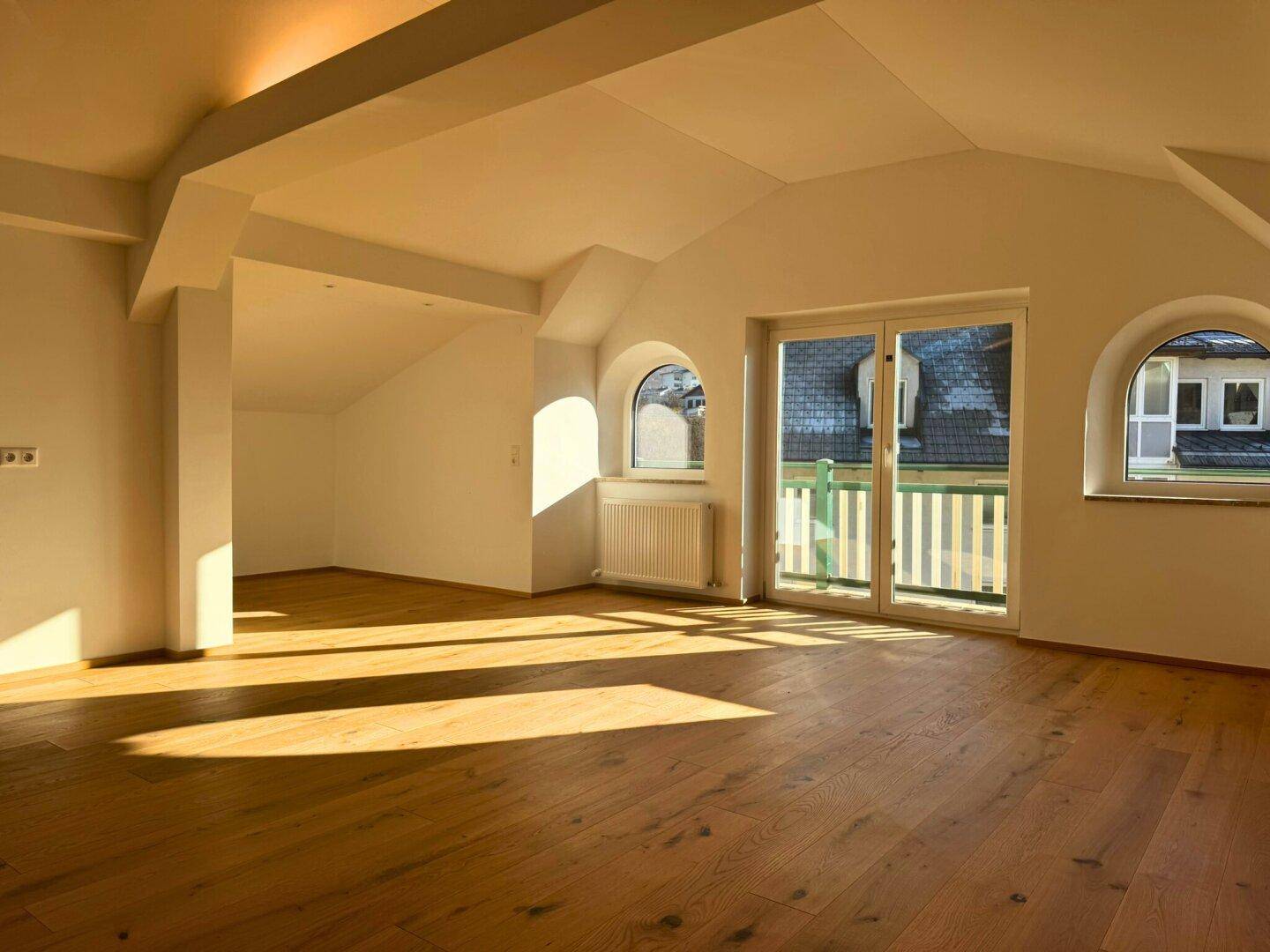 Heller Wohnbereich mit Holzboden, Dachschrägen und Blick ins Grüne.