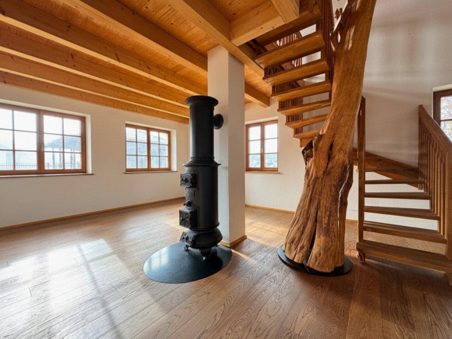 Detailansicht des Wohnbereichs mit rustikalem Holzofen und einzigartiger Baumstamm-Treppe.