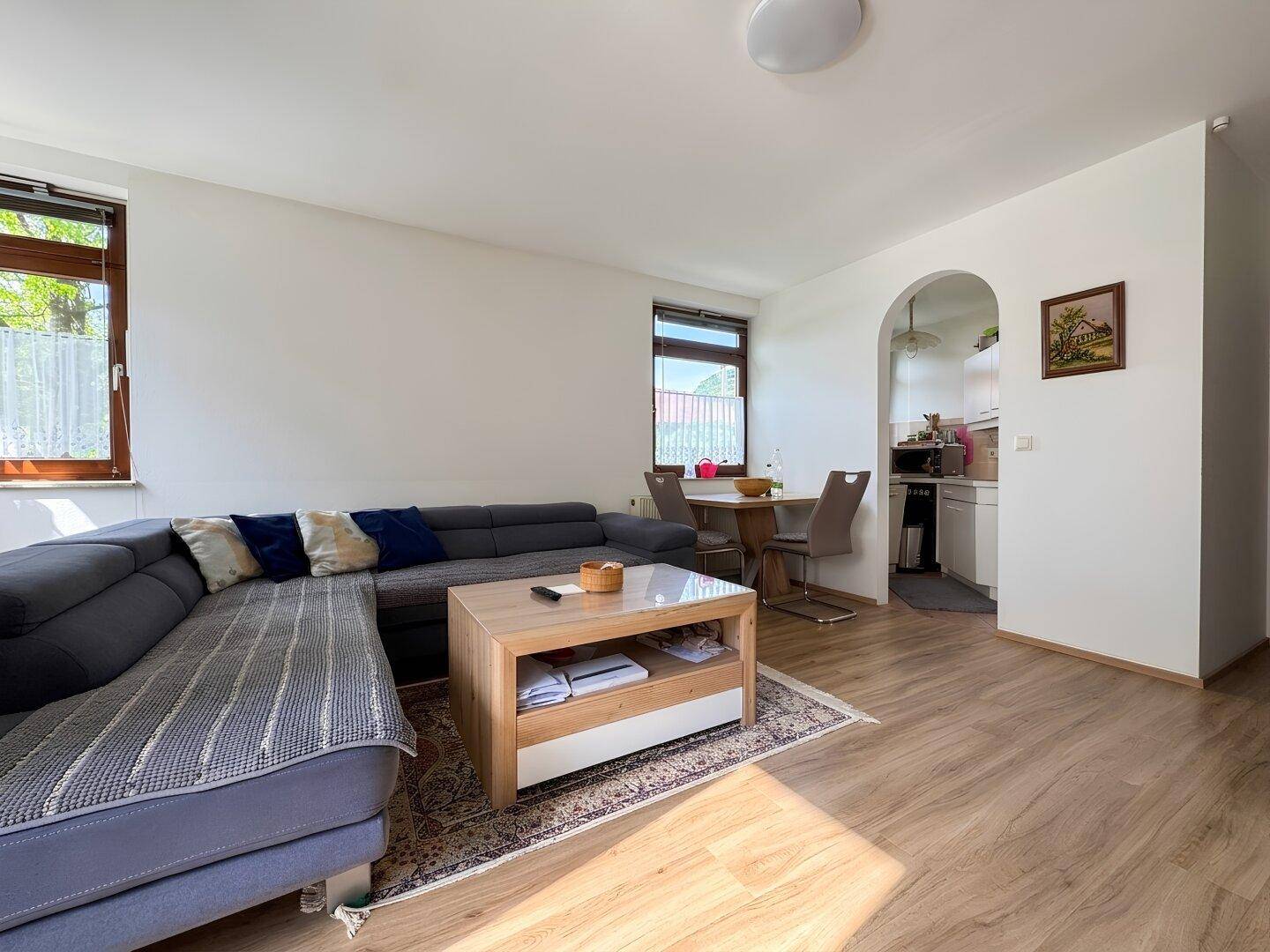 Gemütlicher Wohn- und Essbereich mit Sofa, Esstisch und viel Tageslicht.