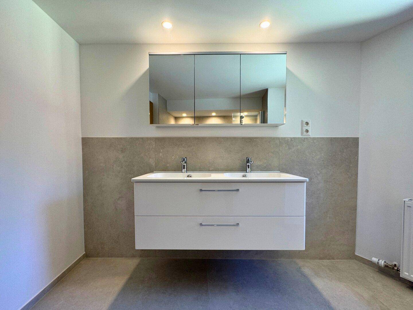 Modernes Badezimmer mit Doppelwaschbecken, Spiegelschrank und indirekter Beleuchtung.