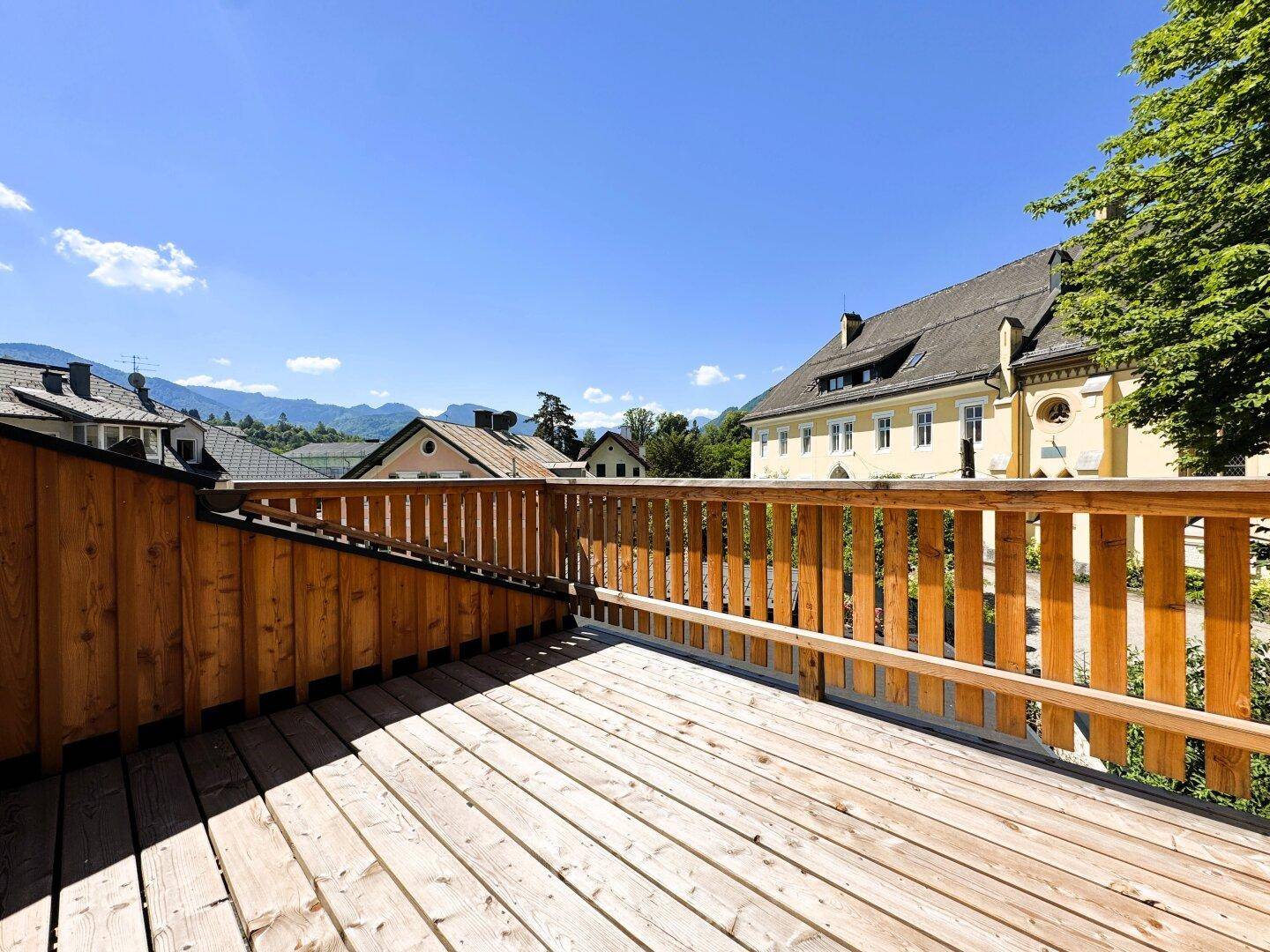 Sonnige Holzterrasse mit Panoramablick auf die Berge und die historische Architektur.