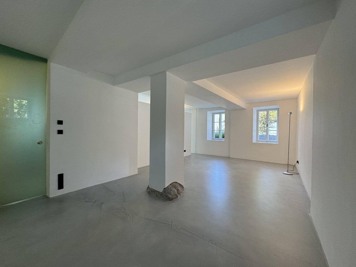 Geräumiger Innenraum mit weiß gestrichenen Wänden, modernem Boden und einem tragenden Pfeiler.