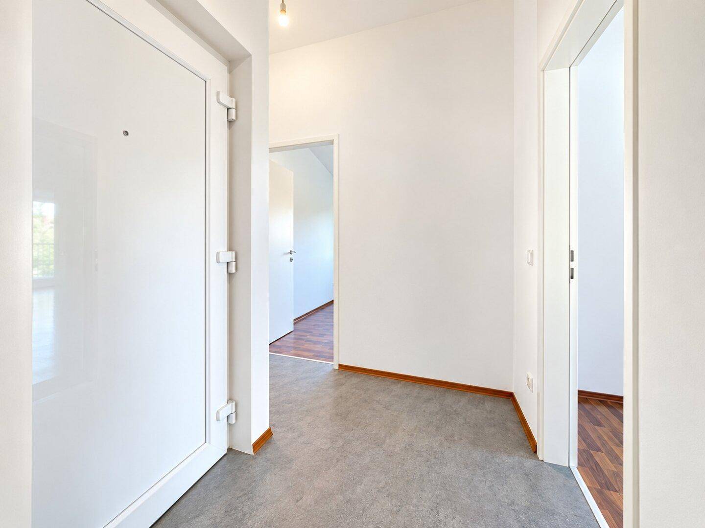 Heller Flur mit grauen Fliesen und weißen Türen, der zu verschiedenen Räumen führt.