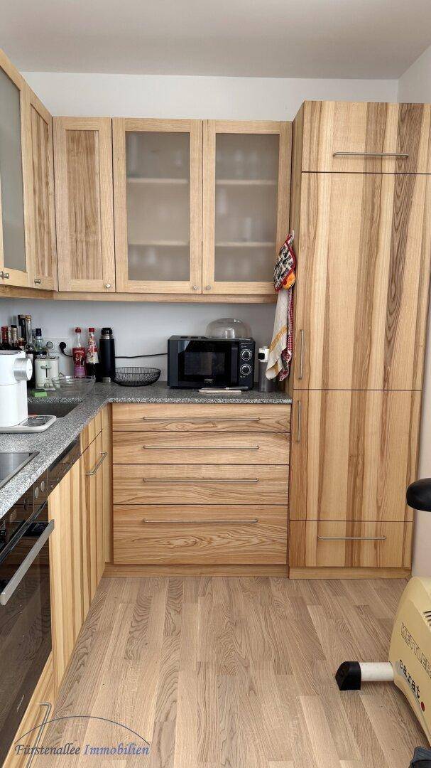 Funktionale Küche mit hellen Holzschränken, Granitarbeitsplatte und integrierten Geräten.