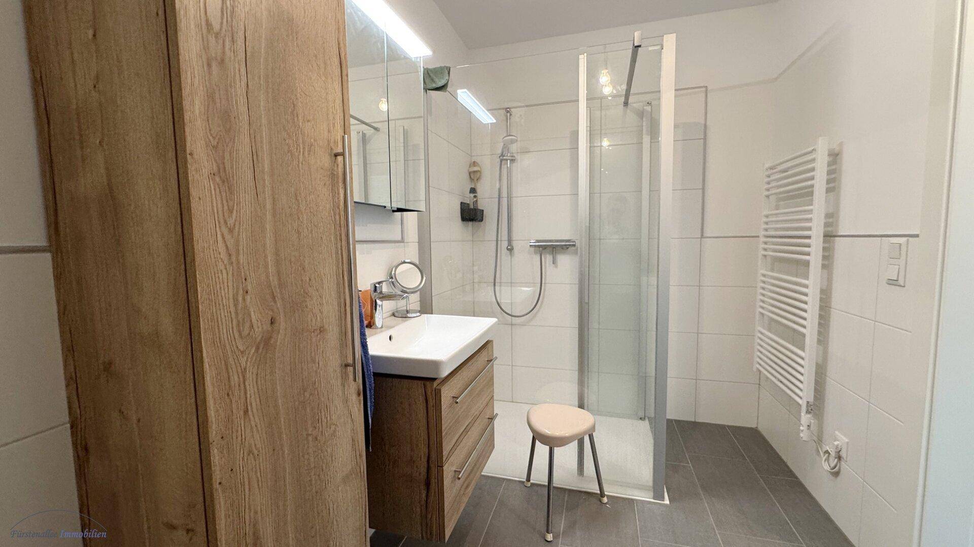 Modernes Badezimmer mit begehbarer Dusche, Einzelwaschbecken und beheiztem Handtuchhalter.