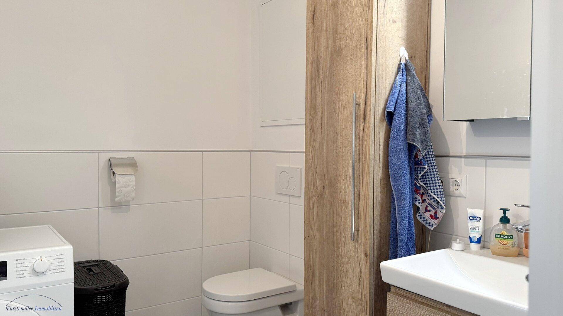 Praktisches Gäste-WC mit Toilette, Waschbecken und integrierter Waschmaschine.