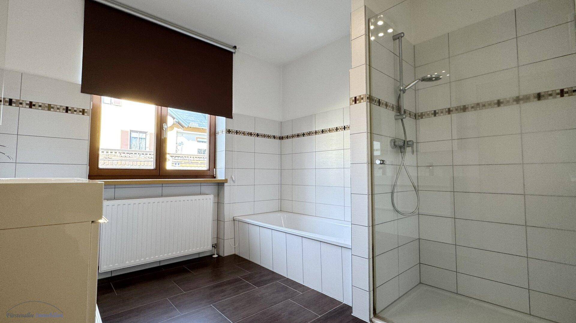 Helles Badezimmer mit Badewanne, Duschkabine und Fenster für natürliche Belüftung.