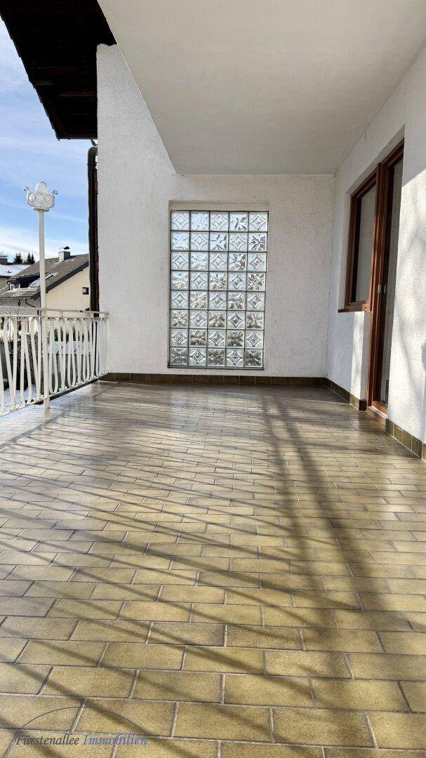 Sonniger Balkon mit Fliesenboden und Blick auf die umliegenden Häuser.