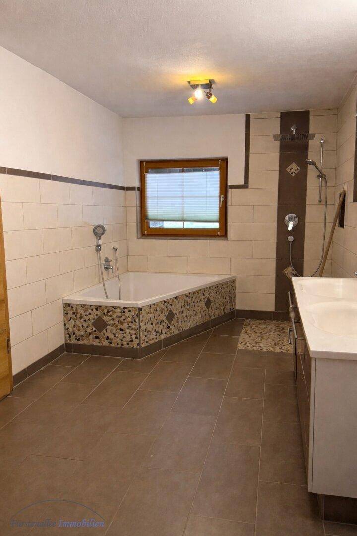 Modern gefliestes Badezimmer mit Eckbadewanne, separater Dusche und Doppelwaschbecken.