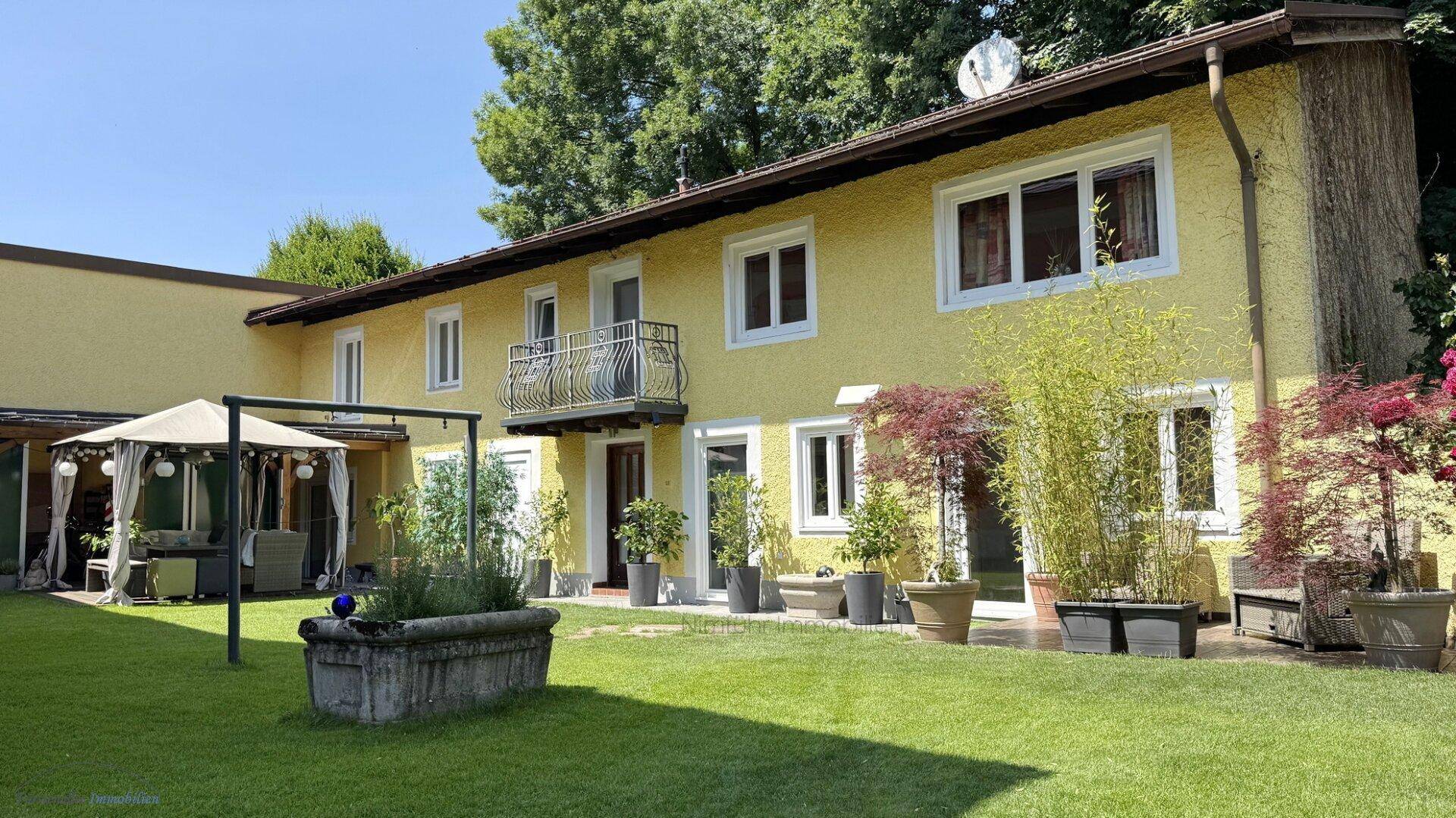 Gelbes Haus mit gepflegtem Garten, Rasenfläche, einem gemütlichen Pavillon und kleinem Balkon.