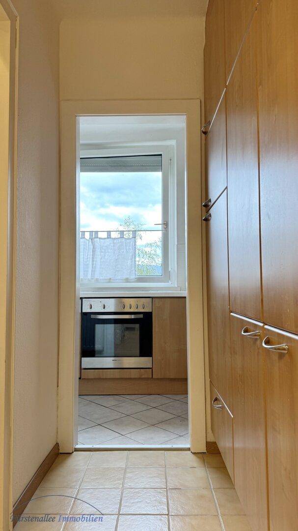 Flur mit praktischen Einbauschränken und Blick in die angrenzende Küche mit Fenster.