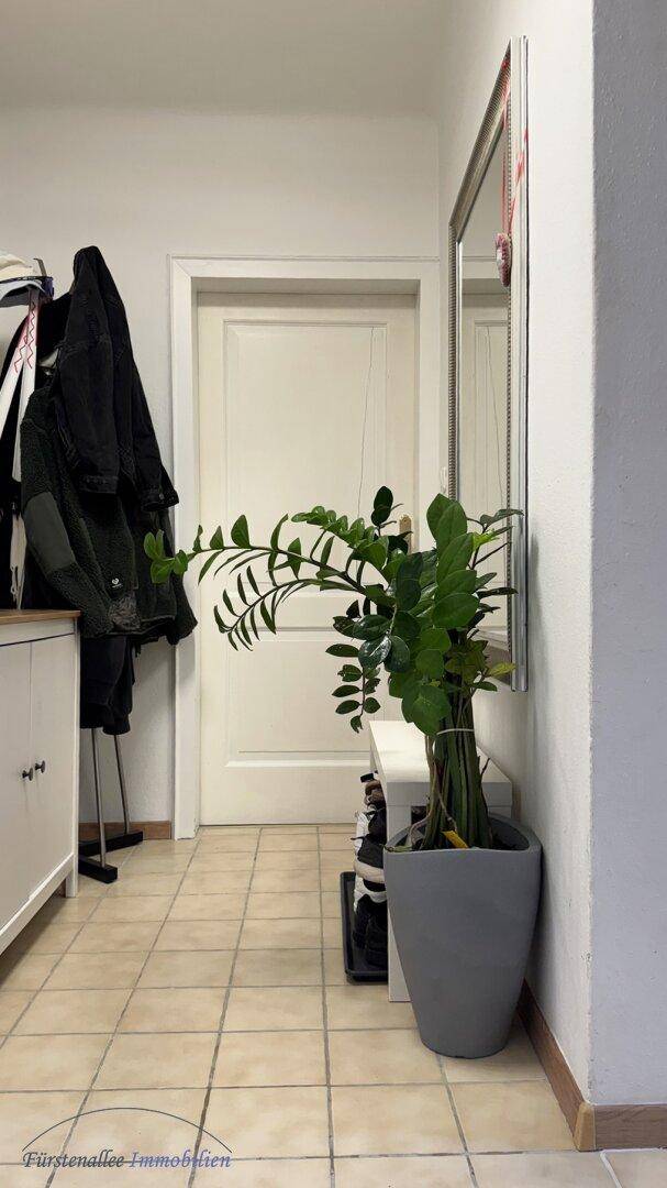 Heller Eingangsbereich mit Fliesenboden, großem Spiegel und Garderobenbereich.