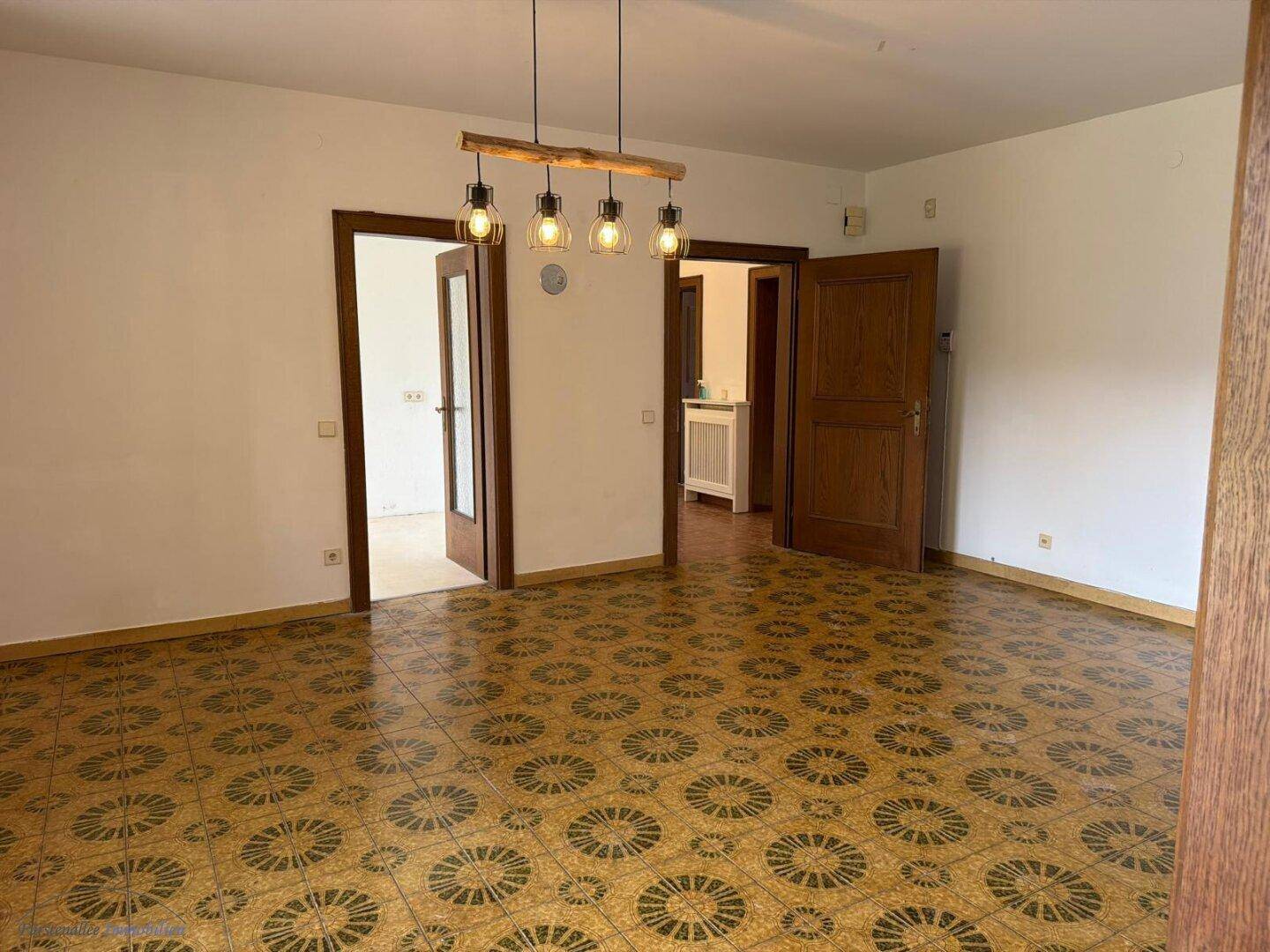 Heller Wohnbereich mit gemustertem Fliesenboden und mehreren Holztüren.