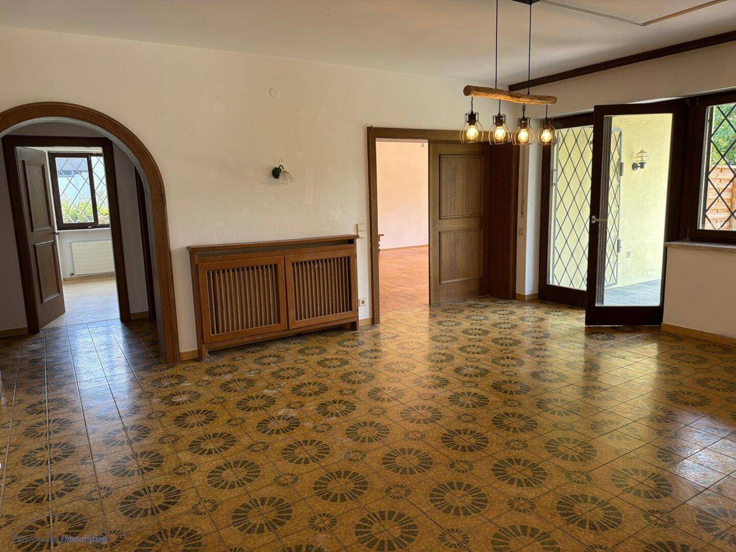 Geräumiger Wohnbereich mit auffälligem Fliesenboden und Zugang zur Terrasse.