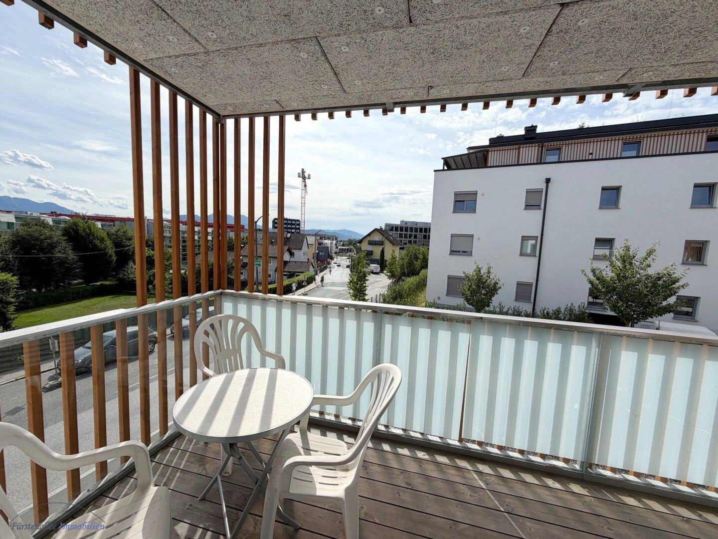Balkon mit Holzboden und Sitzgelegenheiten bietet einen Blick auf die umliegende Wohngegend.