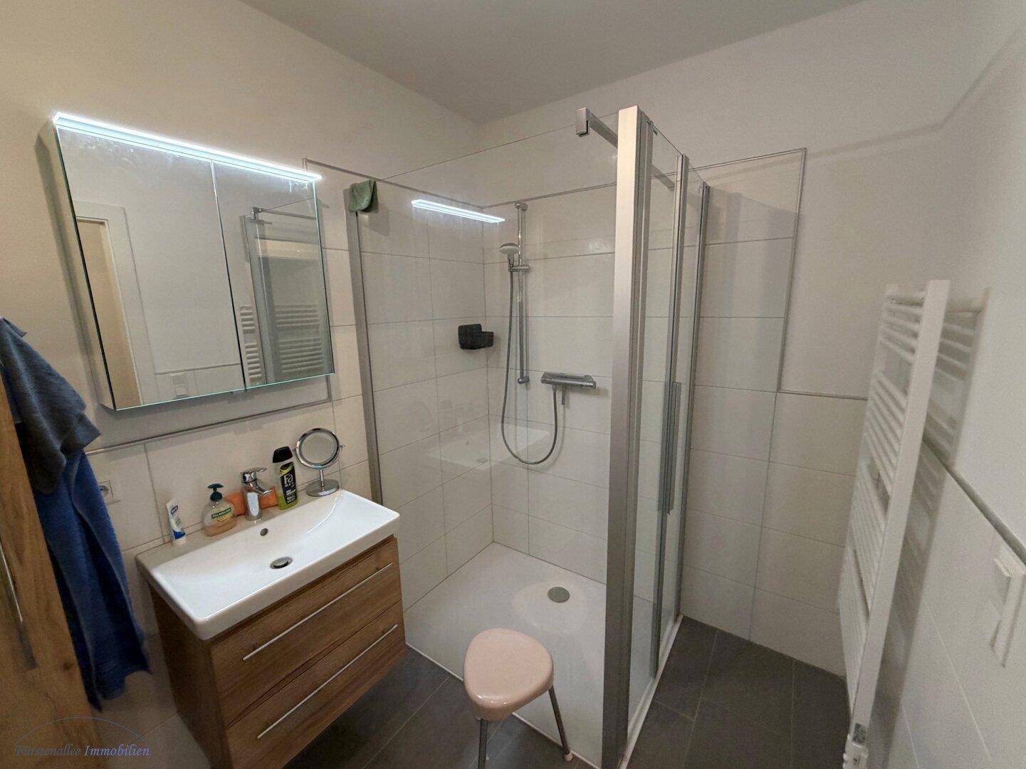 Modernes Badezimmer mit Duschkabine, Einzelwaschbecken und beheiztem Handtuchhalter.