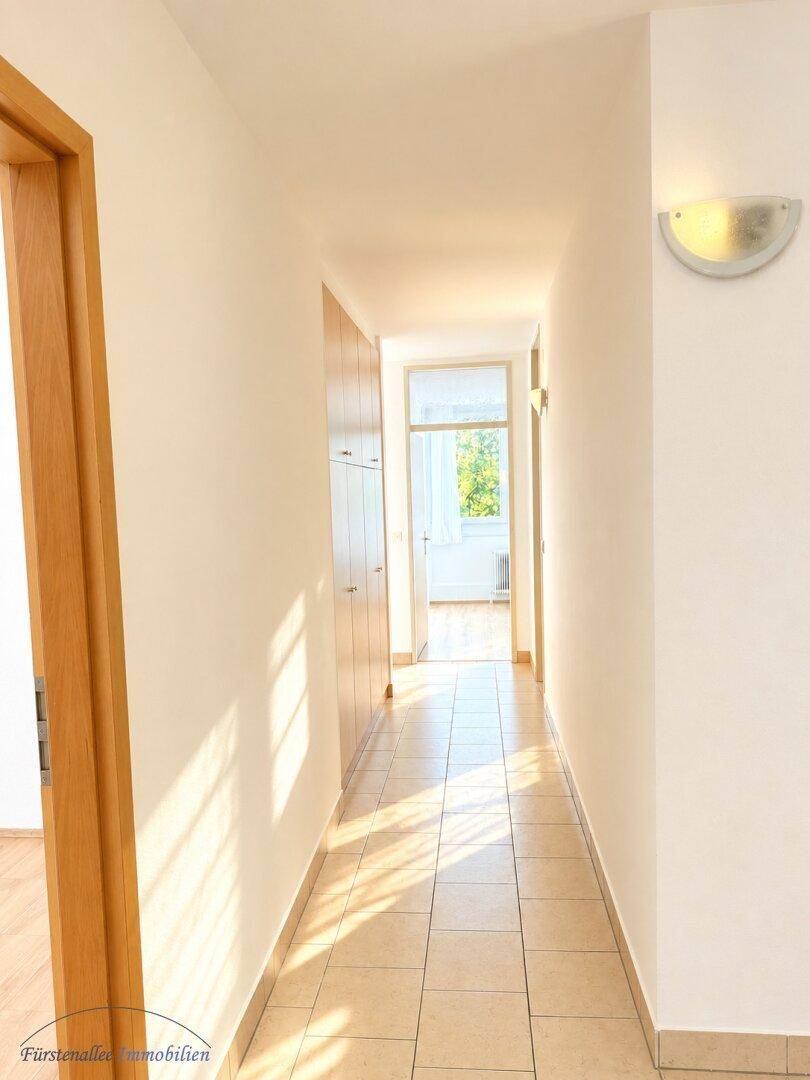 Heller Flur mit Fliesenboden und Einbauschränken, der zu weiteren Räumen der Wohnung führt.