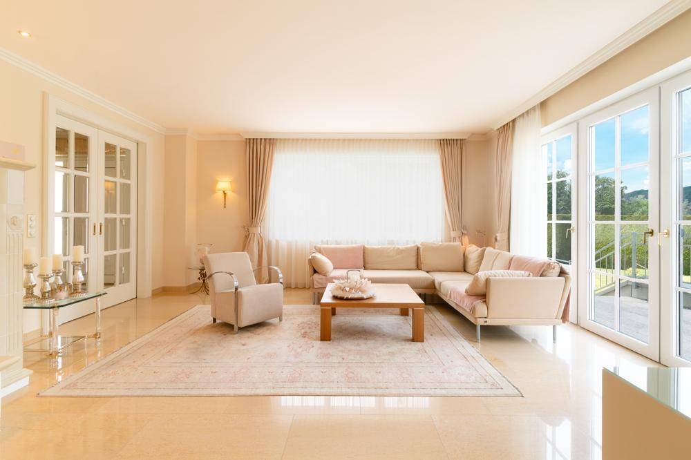 Helles Wohnzimmer mit beigem Sofa, eleganten Möbeln und Zugang zu einem Balkon.