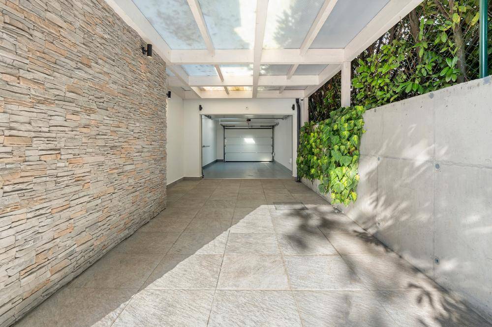 Überdachte Einfahrt mit Steinwand, die zur Garage des Hauses führt.