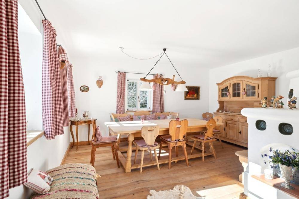 Heller Essbereich mit weiß getünchten Wänden, traditionellen Holzmöbeln und einem Kachelofen.