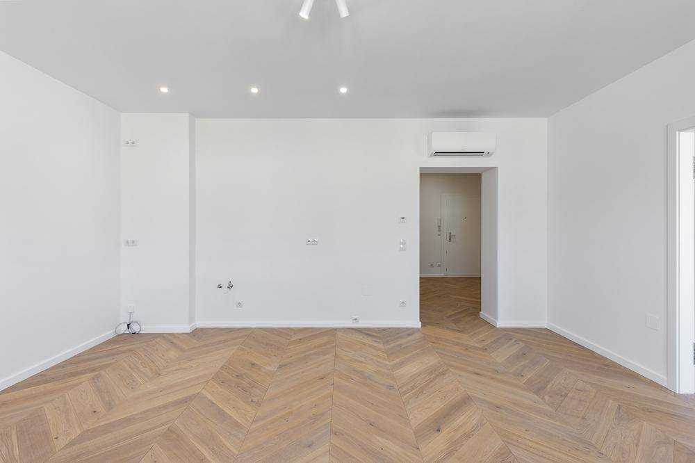 Geräumiges Zimmer mit neuem Fischgrätparkett und weiß gestrichenen Wänden, bereit zum Einrichten.