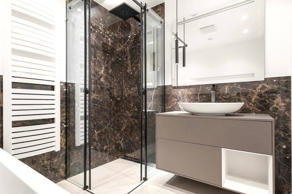 Modernes Badezimmer mit dunklen Marmorfliesen, begehbarer Dusche und stilvollem Waschbecken.