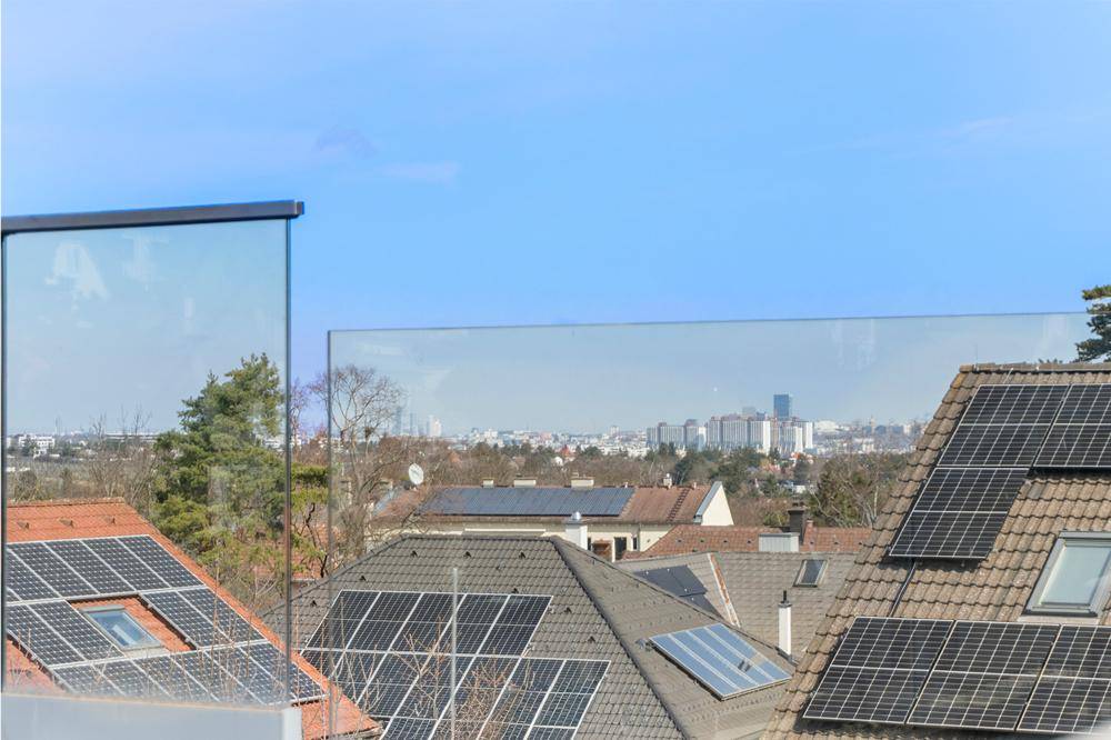 Weitblick von der Dachterrasse über Dächer mit Solaranlagen und die Stadt.