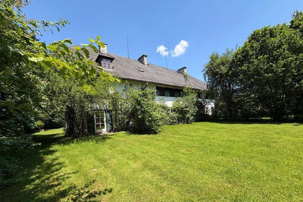 Großer, gepflegter Garten mit Rasenfläche und altem Baumbestand um das Haus.