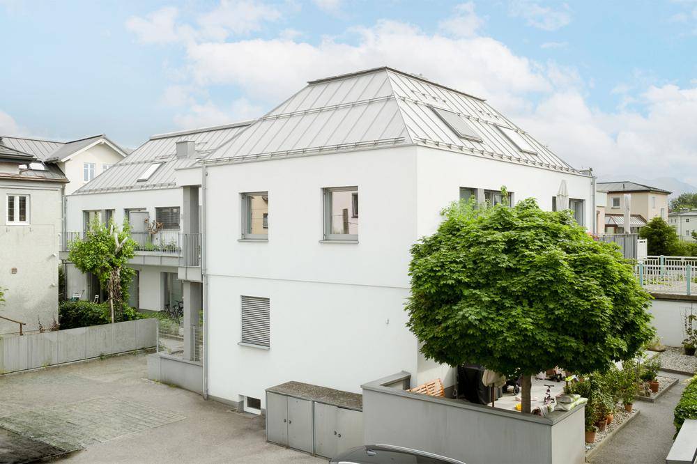 Ansicht des modernen Gebäudes mit weißer Fassade, großen Fenstern und gepflegtem Außenbereich.