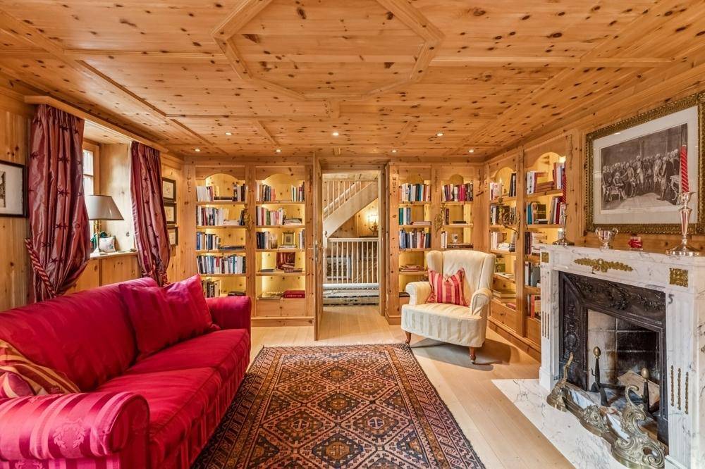 Gemütlicher Wohnbereich mit Holzeinbauten, Kamin und Zugang zu einem Treppenhaus im Landhausstil.