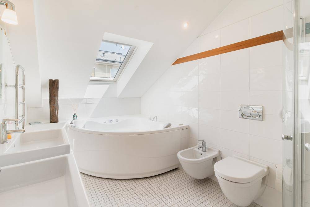 Modernes Badezimmer mit Eckbadewanne, Bidet und Dachfenster.