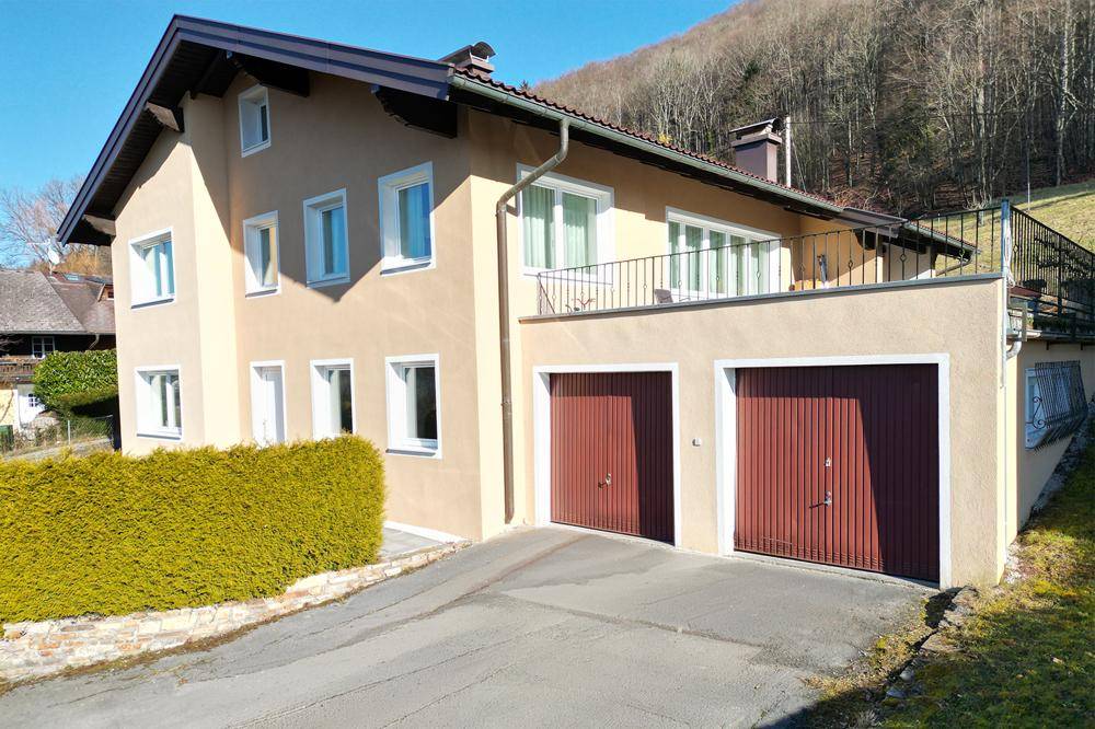 Seitenansicht des Einfamilienhauses mit Doppelgarage und großer Terrasse im Obergeschoss.