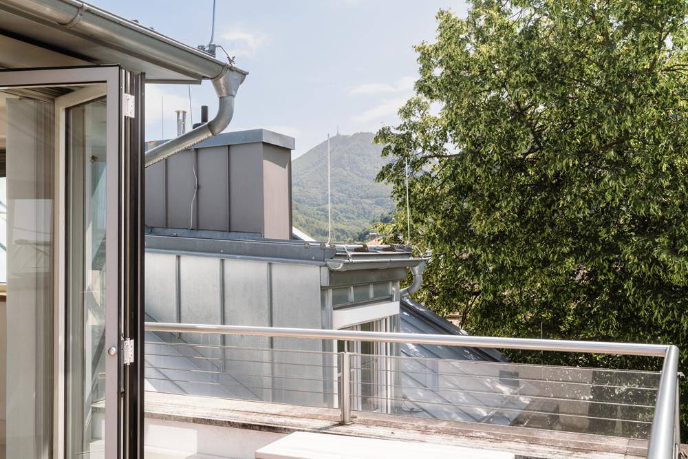 Blick von der Terrasse auf die Dächer der Stadt und die umliegende Berglandschaft.