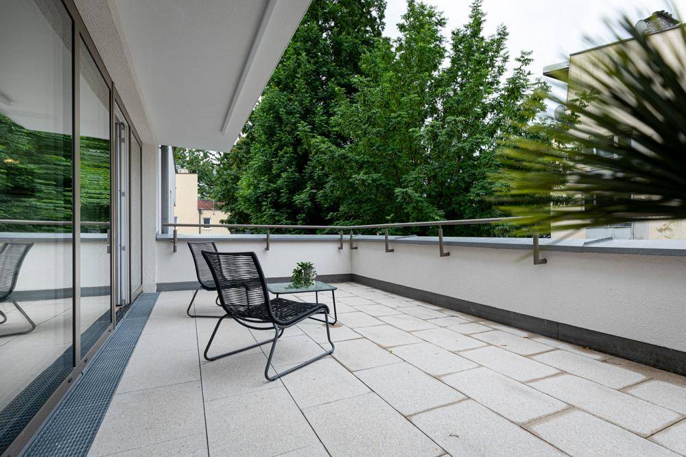Geräumiger Balkon mit modernen Sitzgelegenheiten und Blick ins Grüne, ideal zum Entspannen.