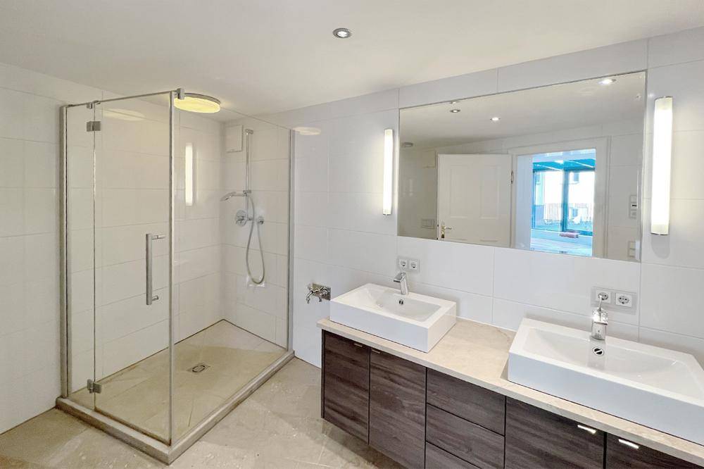 Das freundliche Badezimmer mit Doppelwaschbecken und Dusche