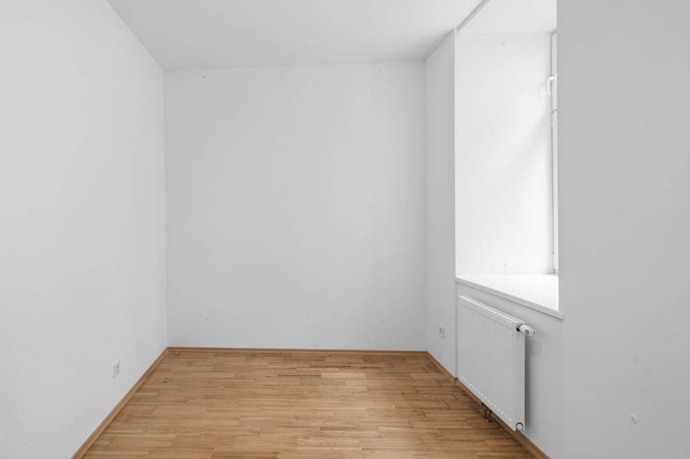 Kleiner, heller Raum mit Holzboden und Fenster.