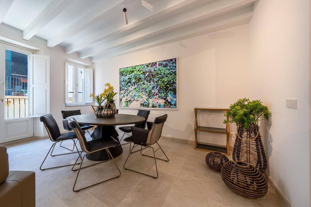 Heller Essbereich mit modernem runden Tisch, Designerstühlen und Kunstwerk an der Wand.