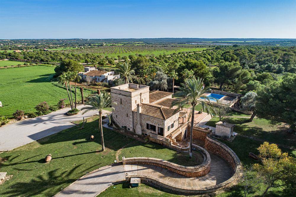 Luftaufnahme des Anwesens mit großem Haus, Pool und weitläufiger grüner Landschaft in der Umgebung.