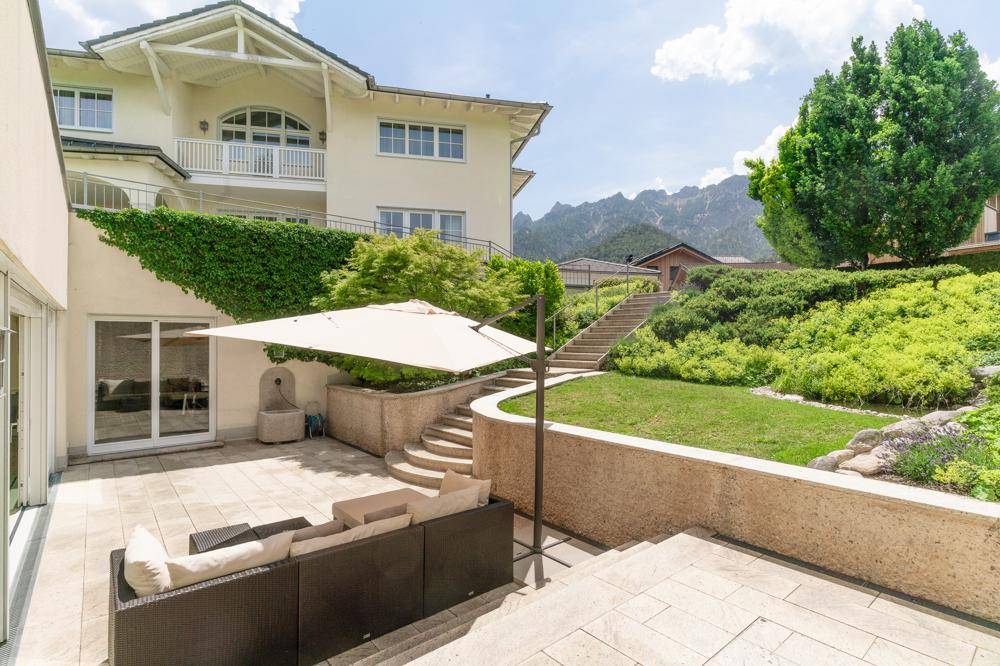 Geräumige Terrasse mit Lounge-Möbeln und Treppen, die zum Garten und Haus führen.