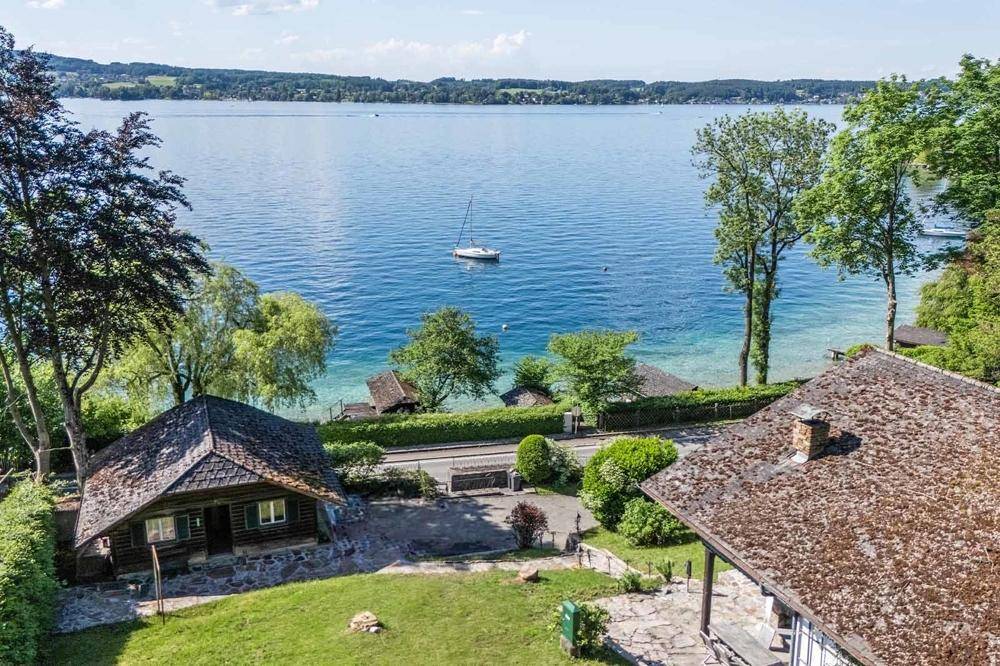 Panoramablick auf den glitzernden See mit zwei charmanten Häusern und üppiger grüner Umgebung.