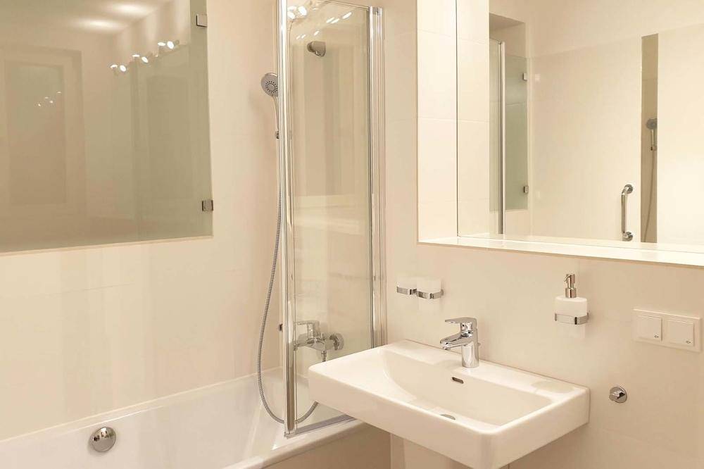 Modernes Badezimmer mit Badewanne, Duschabtrennung und Einzelwaschbecken in hellem Design.
