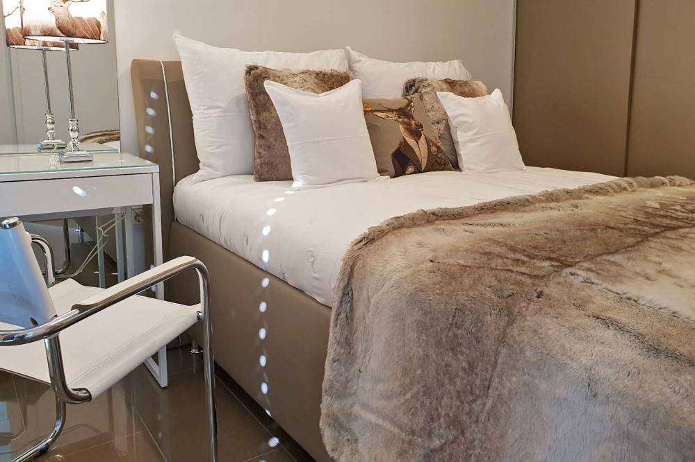 Gemütliches Schlafzimmer mit großem Bett, weicher Decke und modernem Nachttisch.