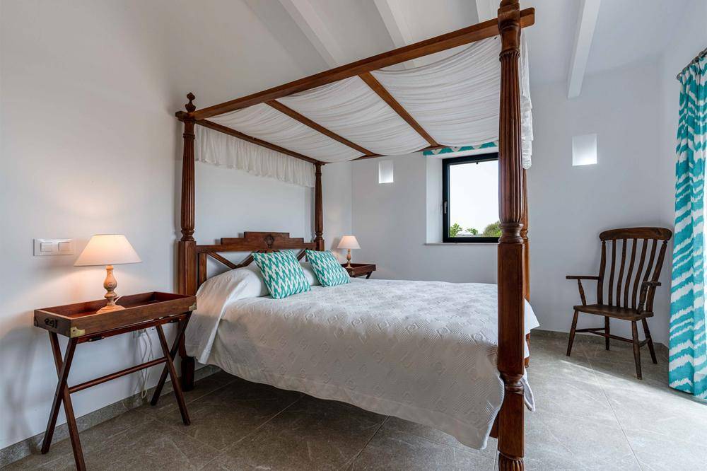 Gemütliches Schlafzimmer mit Himmelbett, Holzbalken und schlichtem, elegantem Design.