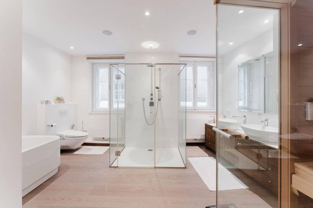 Modernes Badezimmer mit Doppelwaschbecken, großer Glasdusche, Badewanne und Sauna.