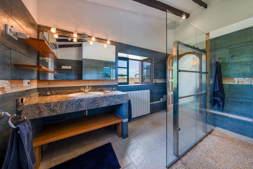Modernes Badezimmer mit Granitwaschtisch, begehbarer Dusche und Fenster.